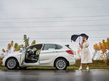 Frau hält Ihr Auto mitten im Regen wegen Reifenpanne am Seitenstreifen an